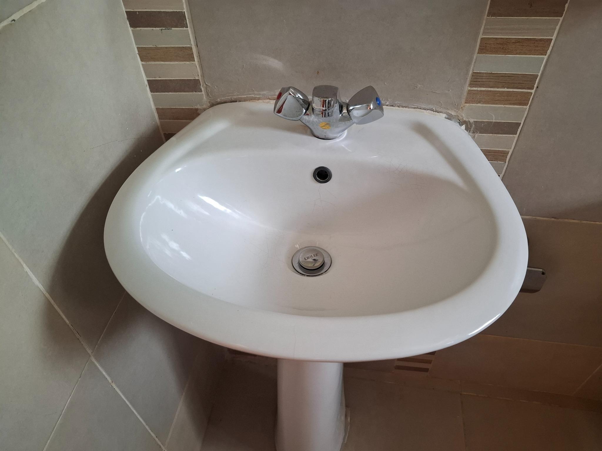Finishing details: a cleaned basin and tap, ready for the final walkthrough.