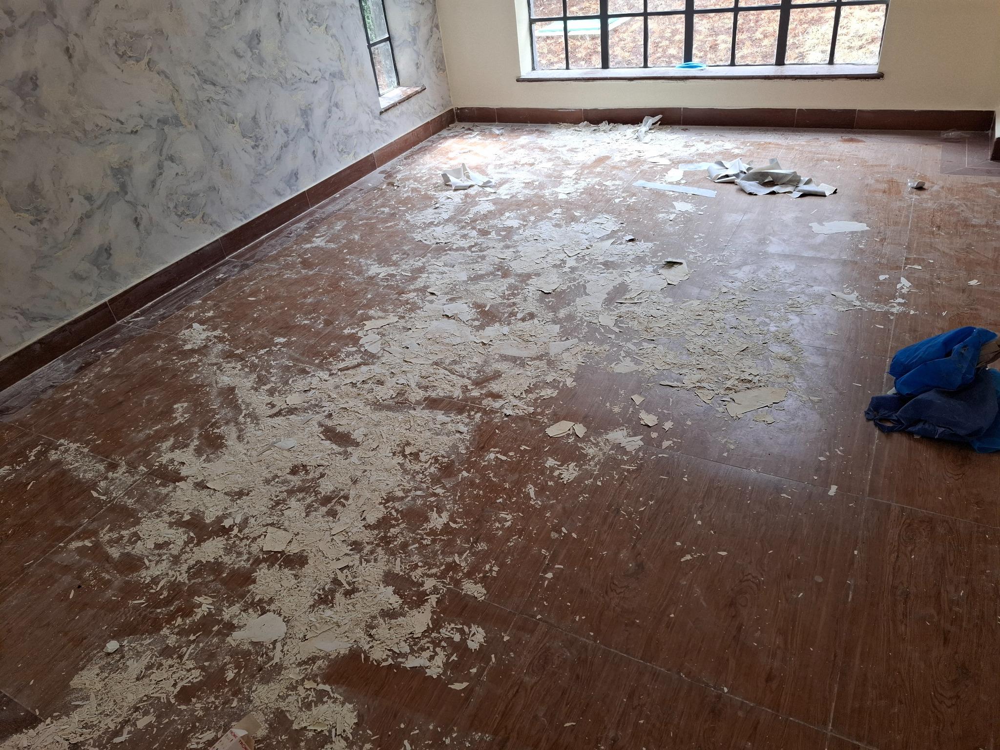 Before cleaning: renovation dust and loose debris across a tiled room.